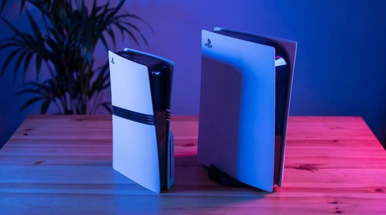 Zwei Spielkonsolen auf einem Tisch, eine kleinere und eine größere, in einem Raum mit blauer und rosa Beleuchtung.