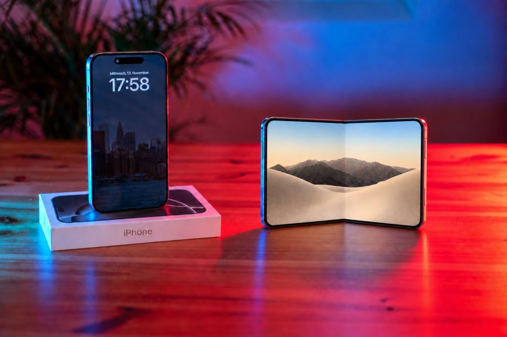 KI-generiertes Symbolbild: iPhone 16 Pro Max auf seiner Verpackung neben einem aufgeklappten faltbaren Smartphone